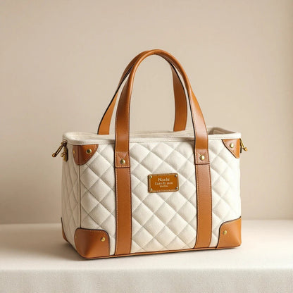 Larkwell The Voyager cream quilted bouclé dog carrier with tan leather handles, brass hardware, and structured frame.